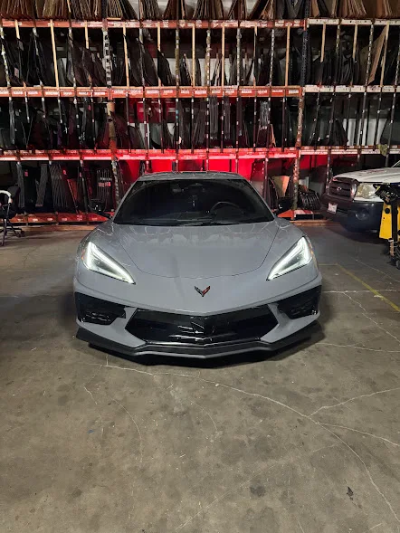 Sports car in the Majesty Auto Glass shop surrounded by glass inventory